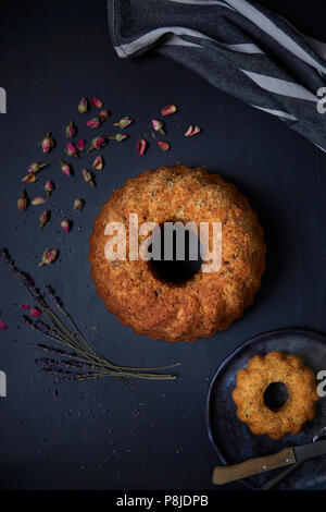 Walnut and Carrot pound cake with dry roses and lavender. Black background, top view Stock Photo
