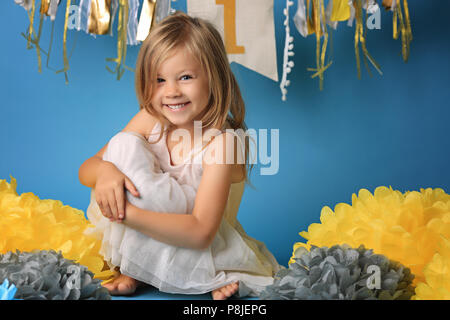 Portrait of happy surprised little girl in princess dress with open mouth and waving hands isolated on blue background Stock Photo