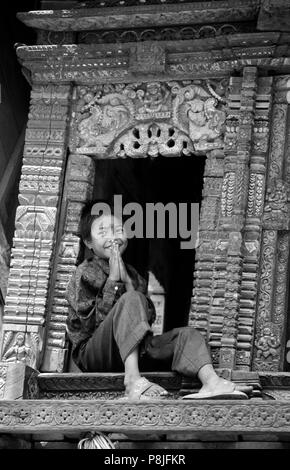 A boy signs NAMASTE meaning I salute the God within You, as he sits in a CHARIOT used in a local festival - BHAKTAPUR, NEPAL Stock Photo