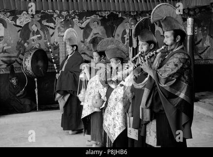 BUDDHIST yellow hat MONKS play TRUMPETS to begin the dances, TIKSE Monastery Masked Dances - LADAKH, INDIA Stock Photo