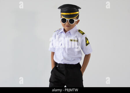 A kindergarten boy standing in dark glasses with a large airline pilot uniform Stock Photo