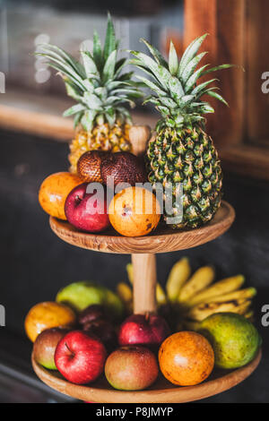 Set of tropical fruits on breakfast reception in hotel. Wooden plate. Pineapple, apple, banana, passionfruit, mango, snake fruit Stock Photo