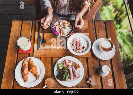 Woman hands holding spoon and having breakfast, view from above Stock Photo