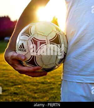Soccer player holding his used adidas tango ball on the field Stock Photo