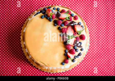 A birthday cake on a glass stand on the table, fruit on top. Top view. Stock Photo