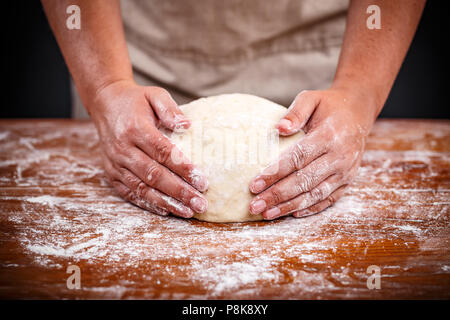 Baker hands making sourdough bread on a wooden table Stock Photo