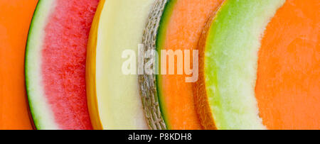 abstract of four different kinds of melon very coloful in a long format ideal for headers, orange background , room for text and copy space Stock Photo