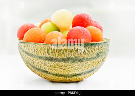 Four different kinds of melon made into ball place in the skin of a century-melon creating a colourful  image with a light background to ad copy space Stock Photo