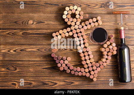 Anchor of wine corks, bottle of wine with corkscrew and a glass of red, viewed from above over dark hardwood table surface with copy space Stock Photo