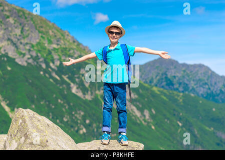 traveler boy enjoys the beauty of the mountains and freedom standing on the rock Stock Photo