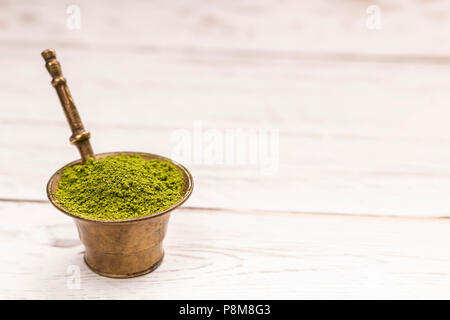Close-up view of matcha green tea in small old bowl on white table Stock Photo