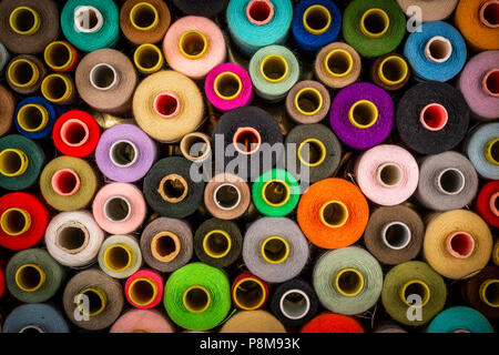 Bright composition of wooden and plastic sewing spools with colorful vibrant threads from above Stock Photo