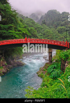 spectacular view of the Shinkyo Bridge over the mountain gorge at Nikko,Tochigi Prefecture,Japan, misty mountains in background and torrent beneath