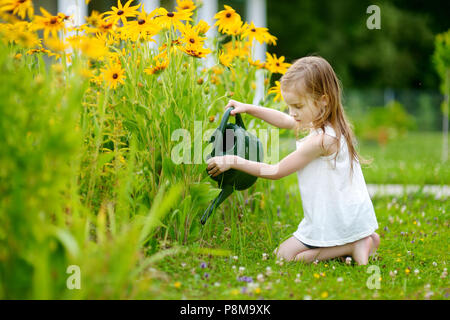 Cute little girl watering plants in the garden Stock Photo