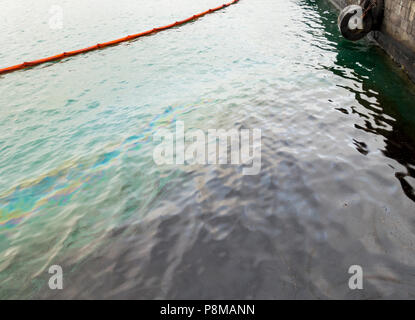 Oil spill containment boom containing oil spill in harbour. Stock Photo