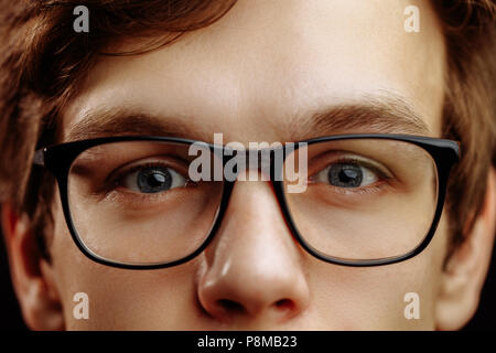 close up half face of handsome fair-haired male with kind blue eyes isolated black background Stock Photo