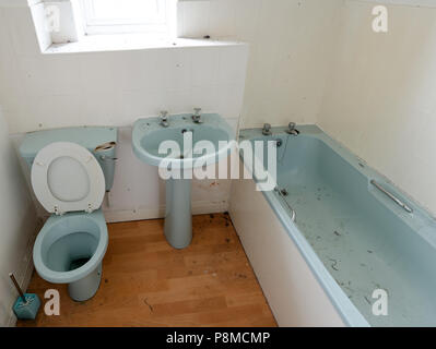 Dirty and dusty bathroom with a toilet which has a broken lid for it's cistern Stock Photo