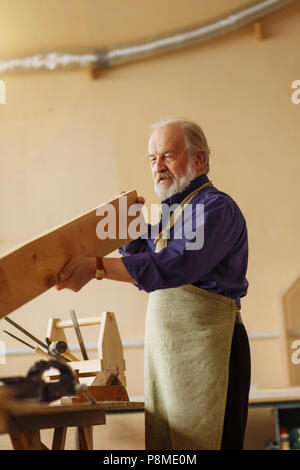 old craftsman defining the length of the board while working indoors Stock Photo