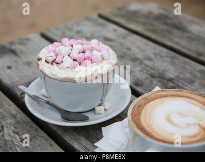 A luxury hot chocolate drink in a posh cup and saucer with whipped cream and marshmallows melting and dribbling down the cup Stock Photo