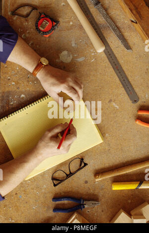vertical top view image of man's hands on the carpener's desk with working tools Stock Photo