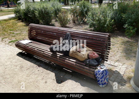 Man sleeping rough on park bench at near Cathedral Island Wrocław Poland Stock Photo