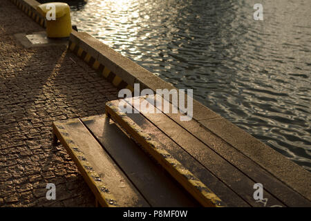 concrete pier with little steps and yellow mooring in evening summer light Stock Photo