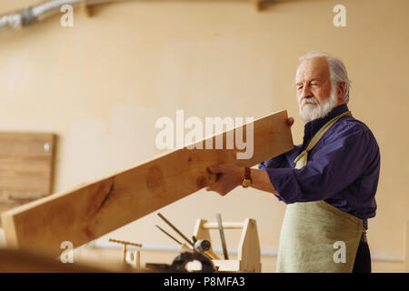old male in special clothes using planks in building in the workshop Stock Photo