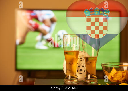 Double exposure of croatian flag and two glasses of beer in front of TV playing football Stock Photo
