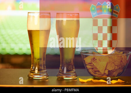 Double exposure of croatian flag and two glasses of beer in front of TV playing football Stock Photo