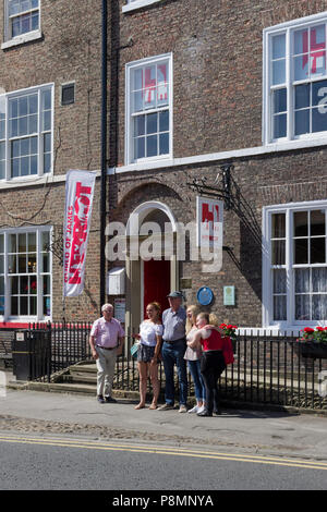 A group of visitors pose outside The World of James Herriott, Thirsk, North Yorkshire; a museum in honour of the famous author and vet. Stock Photo