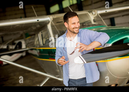 Handsome young pilot checking airplane  in the hangar Stock Photo