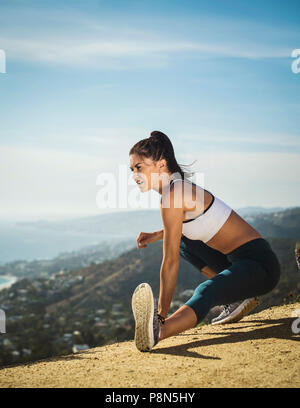 Woman in sportswear stretching on mountain Stock Photo