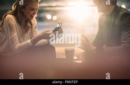 Smiling business colleagues using their smart phones during coffee break in office. Business man and woman sitting in office lounge with their mobile  Stock Photo