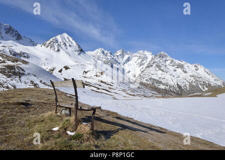 Lonely bench in front of snow covered alpine meadows at the end of the winter at the Col de Lautaret Stock Photo