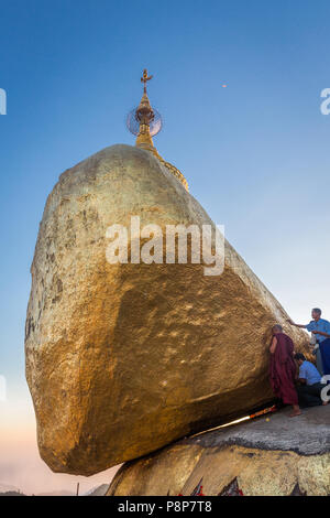 Pilgrims adding gold leaf to Golden Rock, Kyaiktiyo, Myanmar (Burma) Stock Photo