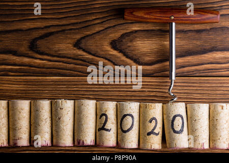 2020 New Year celebration background with a row of used red and white wine corks with an attached bottle opener on a rustic wood background with copy  Stock Photo