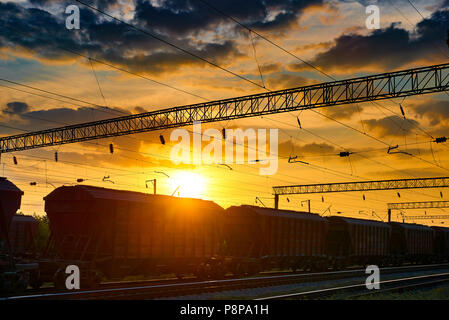 railroad infrastructure during beautiful sunset and colorful sky, railcar for dry cargo, transportation and industrial concept Stock Photo