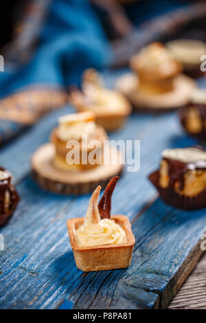 Lemon tart on blue wooden board, other small dessert on background Stock Photo
