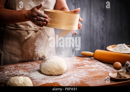 Woman hands sifting flour over dough Stock Photo