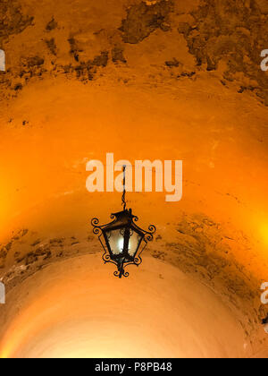 Beautiful old fashioned metal ceiling lantern hanging by chain from curved ceiling with peeling paint Stock Photo