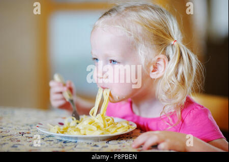 Cute funny little girl eating spaghetti Stock Photo