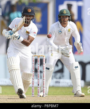Sri Lankan cricketer Dimuth Karunaratne (L) plays a shot as South Africa's Quinton de Kock looks on during the first day of the opening Test match between Sri Lanka and South Africa at the Galle International Cricket Stadium in Galle on July 12, 2018 (Photo by Lahiru Harshana / Pacific Press) Stock Photo
