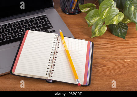 Blank notebook and pencil with a laptop computer on a wooden desktop Stock Photo