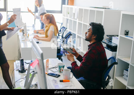 Hindu office worker is operating with culculator. doing the math with calculator. working with financial data Stock Photo