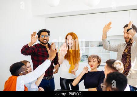 young pleasant people in stylish outfit giving five after getting bonus from the boss Stock Photo