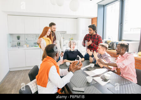 colleagues are applauding their leader and congratulating her with exellent deal during break Stock Photo