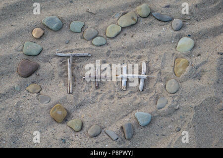 T and H in heart shaped rocks on beach Stock Photo