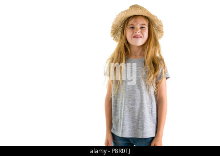 Playful little blond girl in a trendy straw sunhat sticking out her tongue at the camera with a smile isolated on white Stock Photo