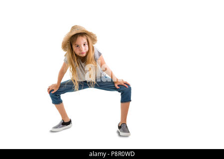 Cute thin young girl in a trendy straw hat and denim jeans crouching down looking at the camera isolated on white with copy space Stock Photo