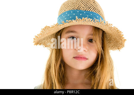 Gentle sincere little girl wearing a trendy straw hat with blue ribbon with a nostalgic serious expression looking pensively at the camera in a close  Stock Photo